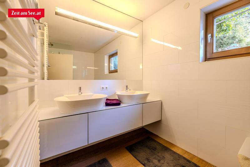 Modernes Badezimmer mit zwei Aufsatzwaschbecken, großem Spiegel und einem Fenster für Tageslicht.