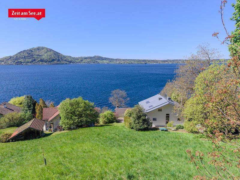 Weitläufige Grünfläche mit einem modernen Haus und Panoramablick auf den See und die Berge.