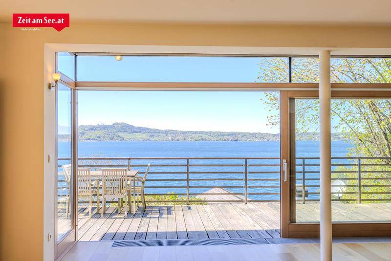 Heller Wohnbereich mit großen Glasfronten, die direkten Zugang zur Terrasse und einen weiten Seeblick bieten.