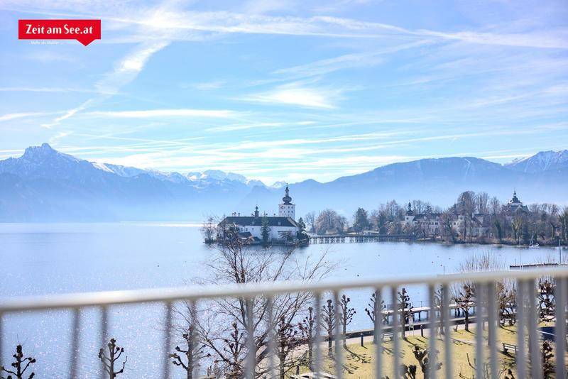 Panoramablick vom Balkon auf den See, ein Schloss und die umliegende Berglandschaft.