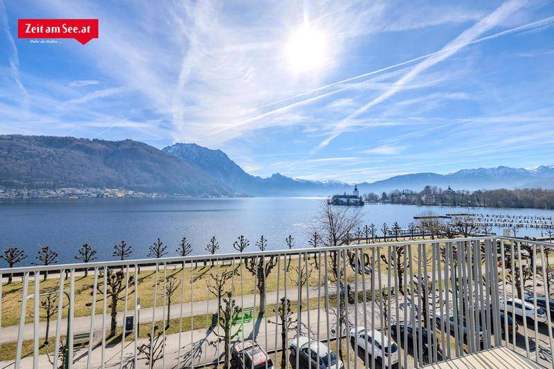 Sonniger Balkon mit weitem Blick über den See, ein Schloss und die majestätischen Berge.