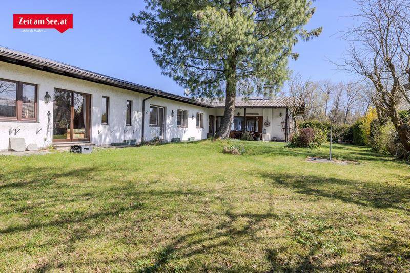 Weitläufiger Gartenbereich hinter dem Haus mit großer Rasenfläche und altem Baumbestand.