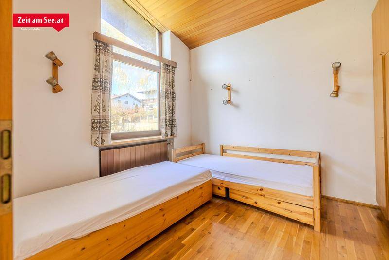 Helles Schlafzimmer mit zwei Einzelbetten aus Holz und Parkettboden.