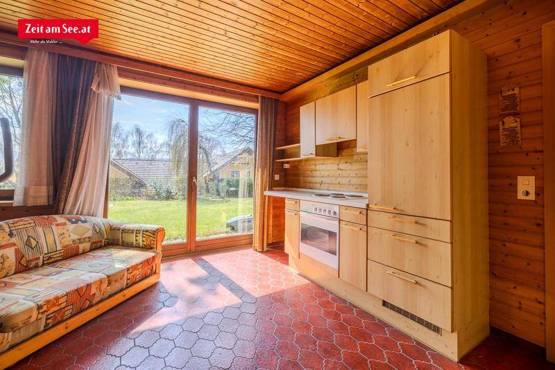 Gemütlicher Wohnraum mit kleiner Küchenzeile, Sofa und Zugang zum Garten.