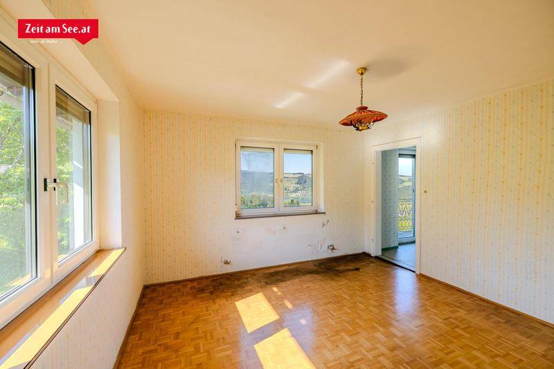 Leeres Zimmer mit Parkettboden und gemusterter Tapete, bereit zur Renovierung.