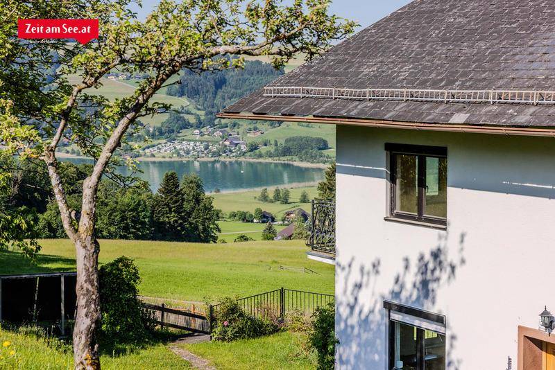 Detailansicht der Hausfassade mit Fenster und schmiedeeisernem Geländer, Blick auf den See.