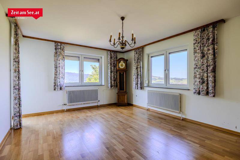 Helles Wohnzimmer mit Holzboden, großen Fenstern und Blick auf die Landschaft.