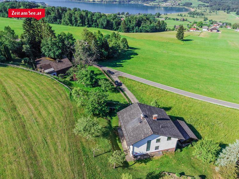 Luftaufnahme des Anwesens mit Haus, Zufahrt und weitem Blick auf den See und die Landschaft.