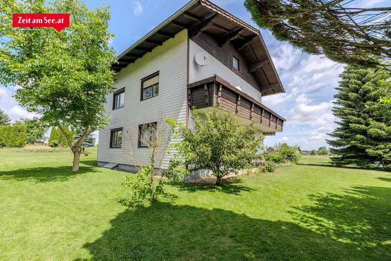 Seitenansicht des Hauses mit großem Garten und üppiger Vegetation an einem sonnigen Tag.