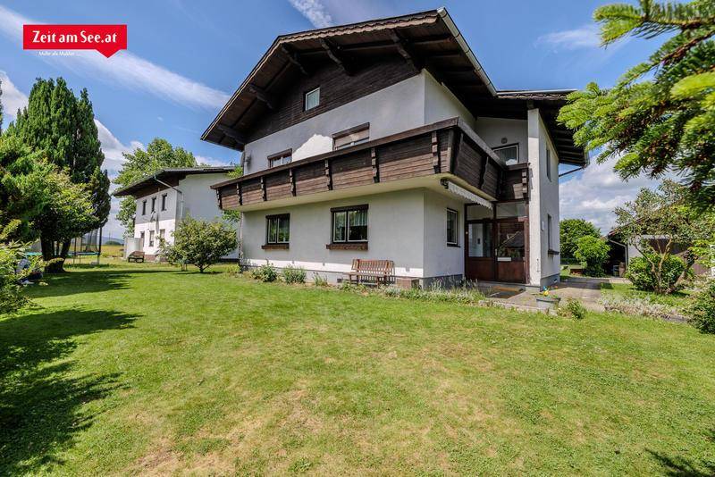 Ansicht des Hauses vom Garten aus mit Balkon und traditioneller Holzverkleidung.