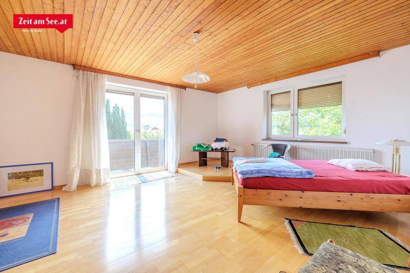 Helles Schlafzimmer mit Holzboden, Holzdecke und Zugang zu einem Balkon mit schöner Aussicht.