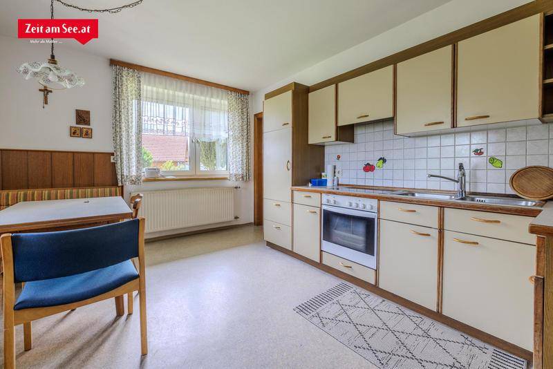 Traditionelle Wohnküche mit Einbaumöbeln, Essbereich und Fenster mit Blick ins Grüne.