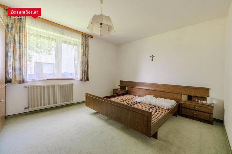 Geräumiges Schlafzimmer mit Teppichboden, Holzmöbeln und großem Fenster für viel Licht.