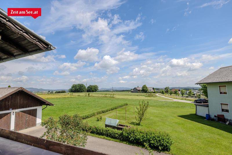 Weitläufiger Blick über grüne Felder und ländliche Umgebung unter einem weiten Himmel.