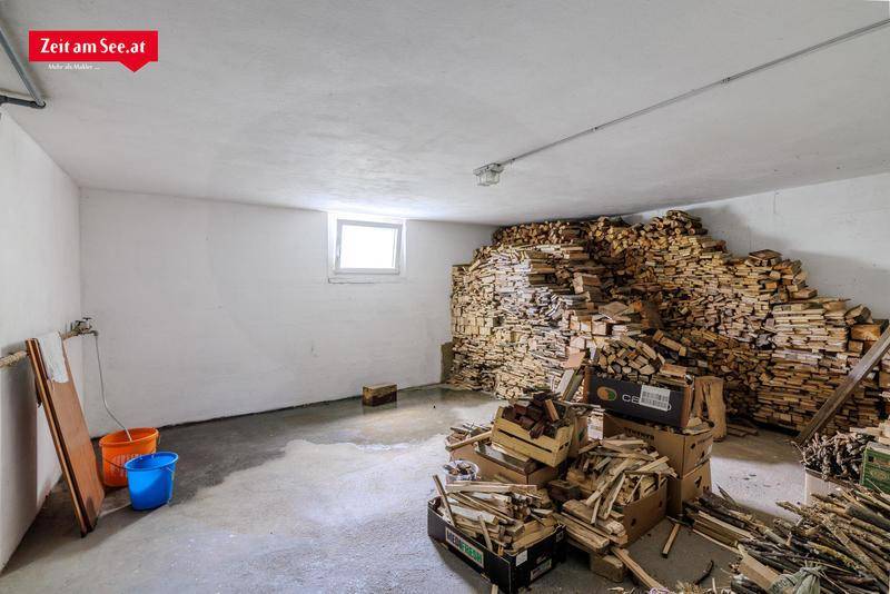 Kellerraum mit großem Holzstapel und Betonboden, geeignet für Lagerung und Heizmaterial.
