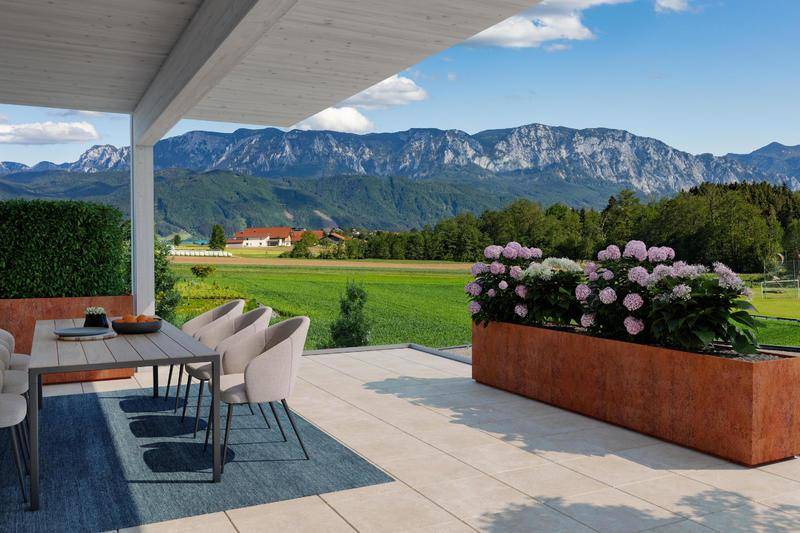 Sonnenterrasse mit Esstisch, Blumenbeeten und atemberaubendem Panoramablick auf die Berge.