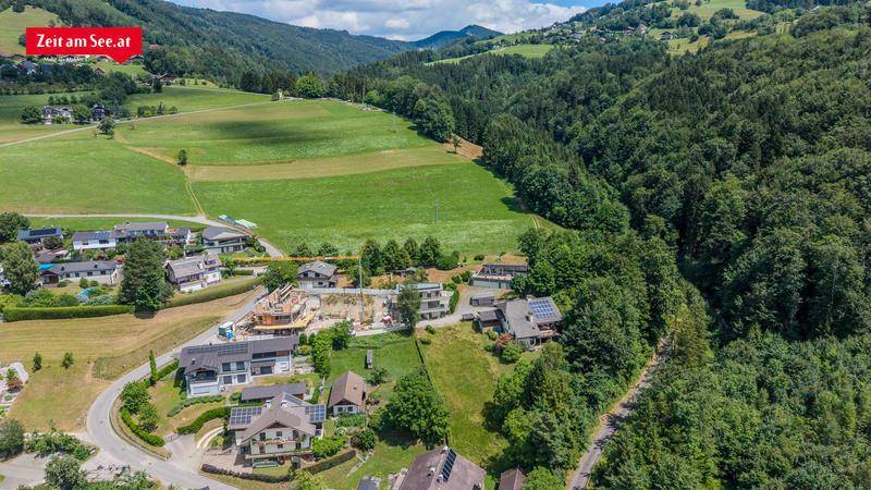 Luftaufnahme einer ländlichen Wohngegend mit Feldern, Wäldern und einem Neubau in der Mitte.