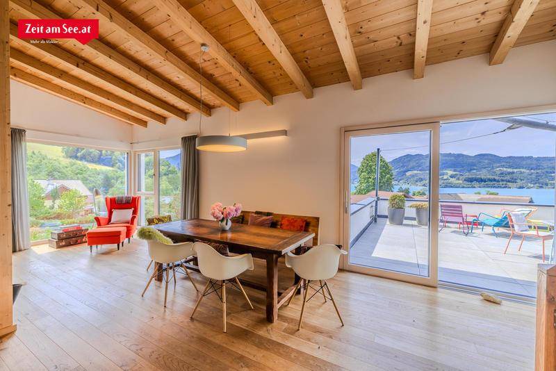 Heller Essbereich mit Holztisch, modernen Stühlen und Zugang zur Terrasse mit Seeblick.