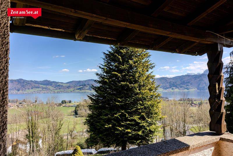 Überdachter Balkon mit weitem Blick auf den See und die bewaldeten Berge.