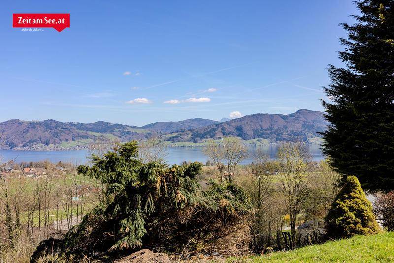 Weitläufiger Blick über die Landschaft mit See und Bergen unter strahlend blauem Himmel.