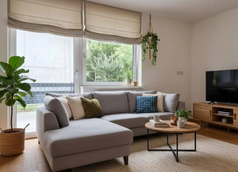Gemütliches Wohnzimmer mit einem großen Ecksofa, Holztisch und weitem Blick ins Grüne.