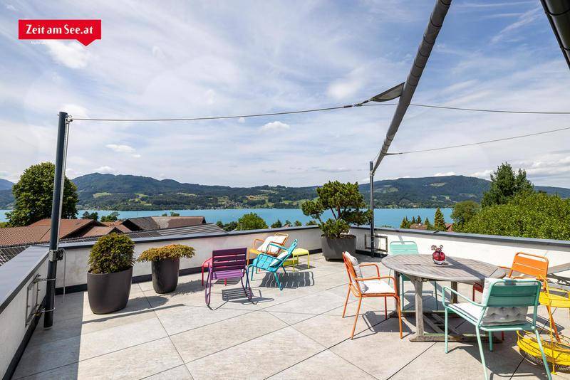 Geräumige Dachterrasse mit bunten Gartenmöbeln und weitem Blick auf den See und die Berge.