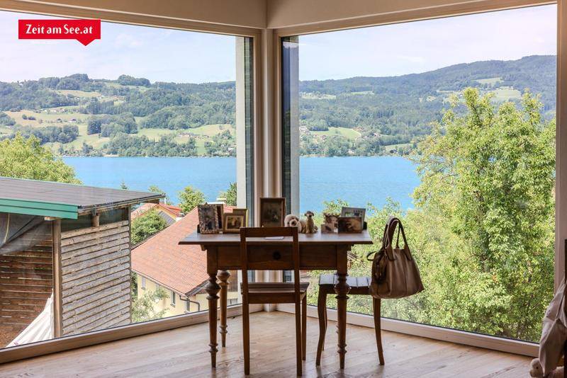 Heller Arbeitsbereich mit großen Fenstern, die einen atemberaubenden Blick auf den See und die umliegende Landschaft bieten.
