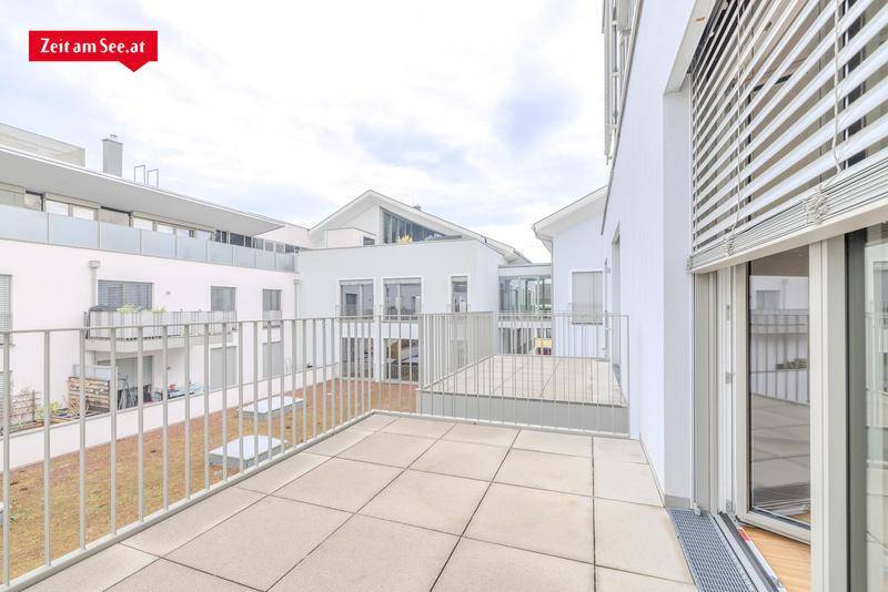 Geräumiger Balkon mit Fliesenboden und Blick auf die moderne Architektur der umliegenden Wohngebäude.