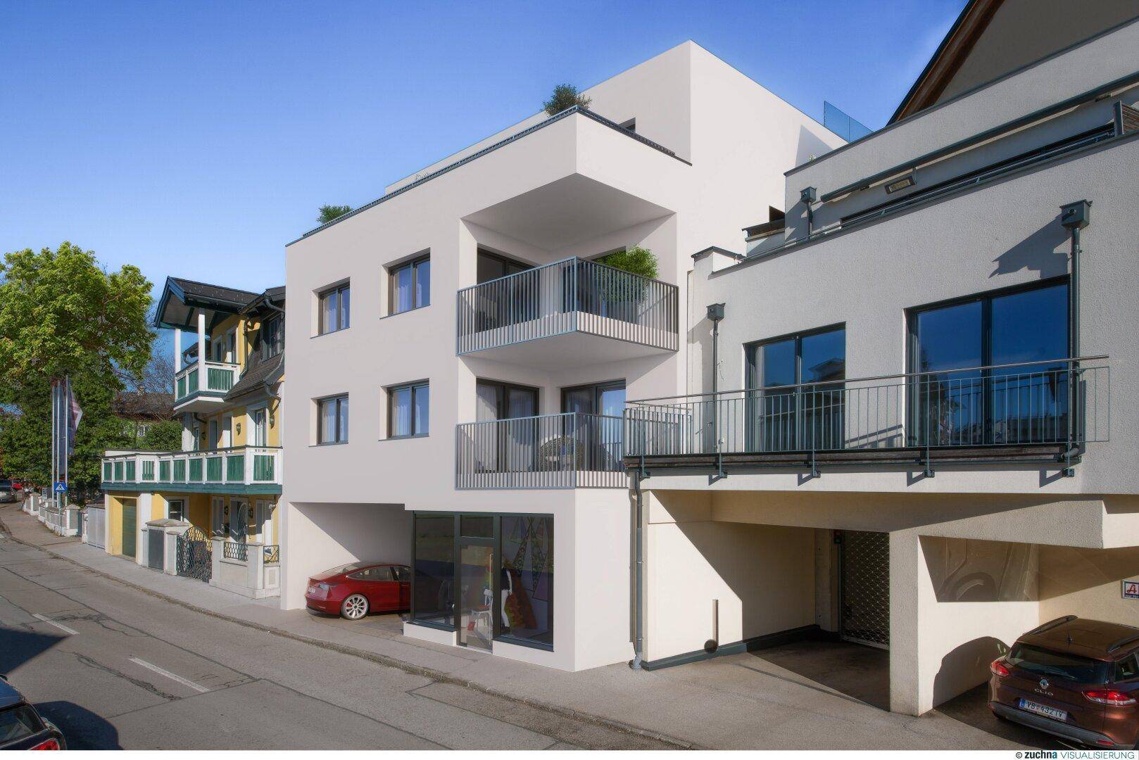 Moderne Wohnanlage mit Balkonen und integrierter Tiefgarage an einer Straße.