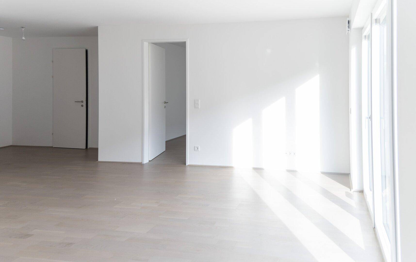 Lichtdurchfluteter Wohnbereich mit hellem Holzboden und mehreren Türen.