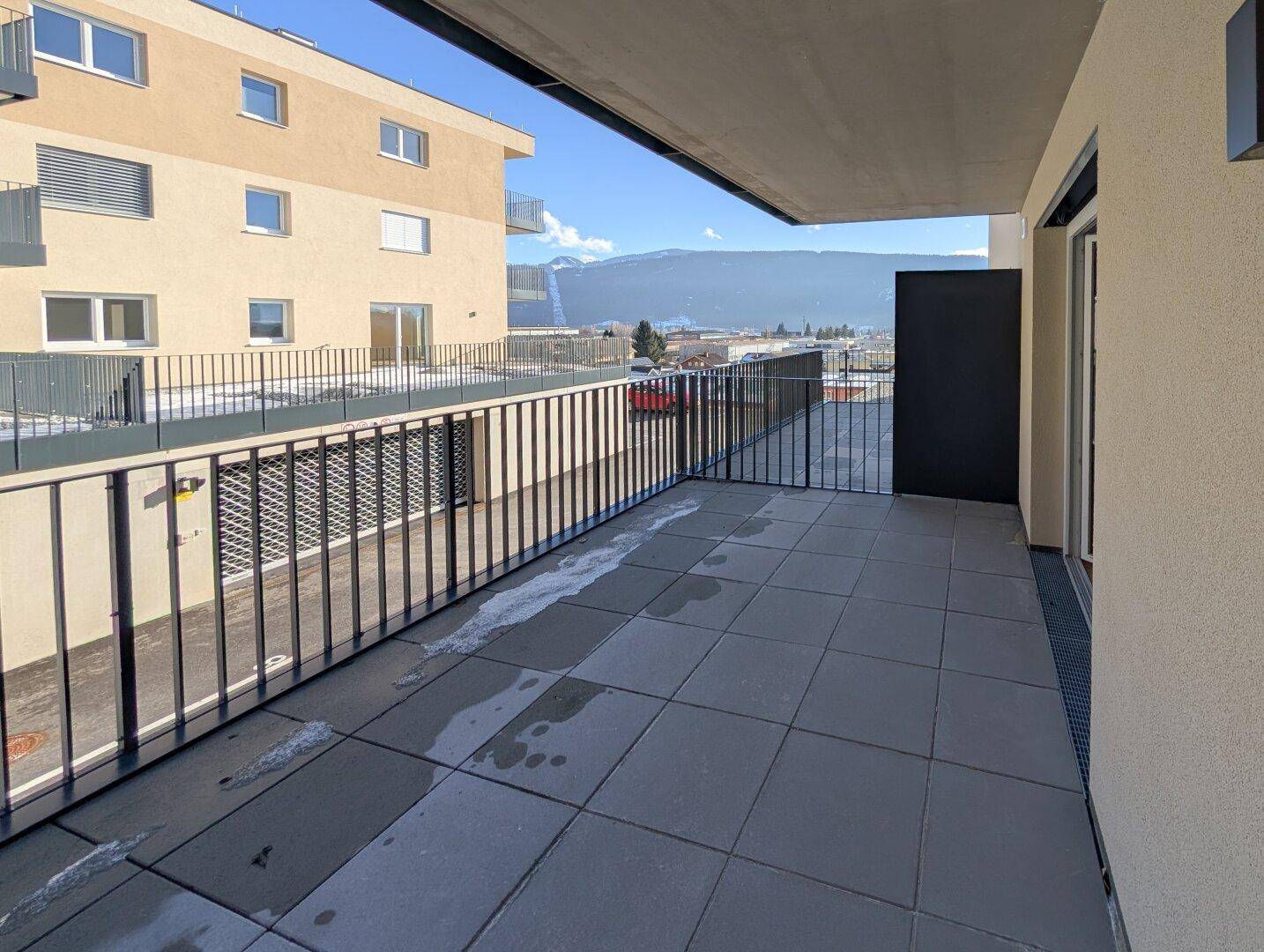 Geräumiger Balkon mit Fliesenboden und weitem Blick auf die umliegende Berglandschaft.