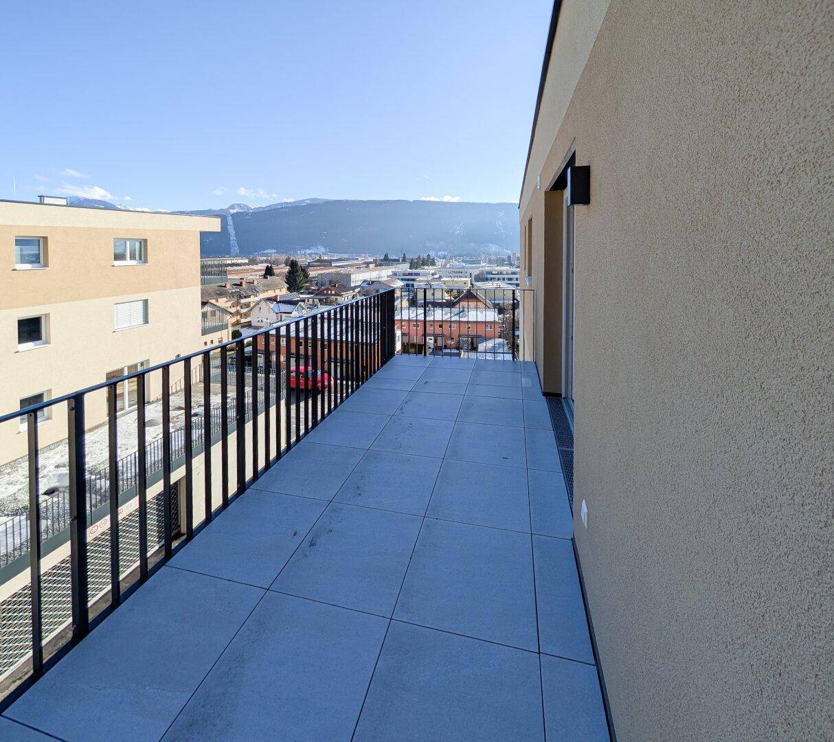 Geräumiger Balkon mit Fliesenboden und weitem Blick über die Stadt und die Berge.