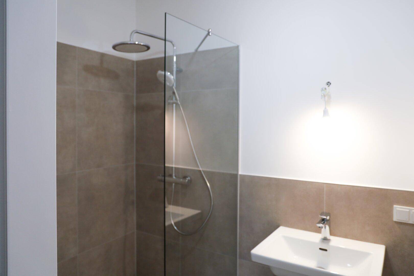 Modernes Badezimmer mit ebenerdiger Dusche, Regenbrause und eleganten Fliesen.