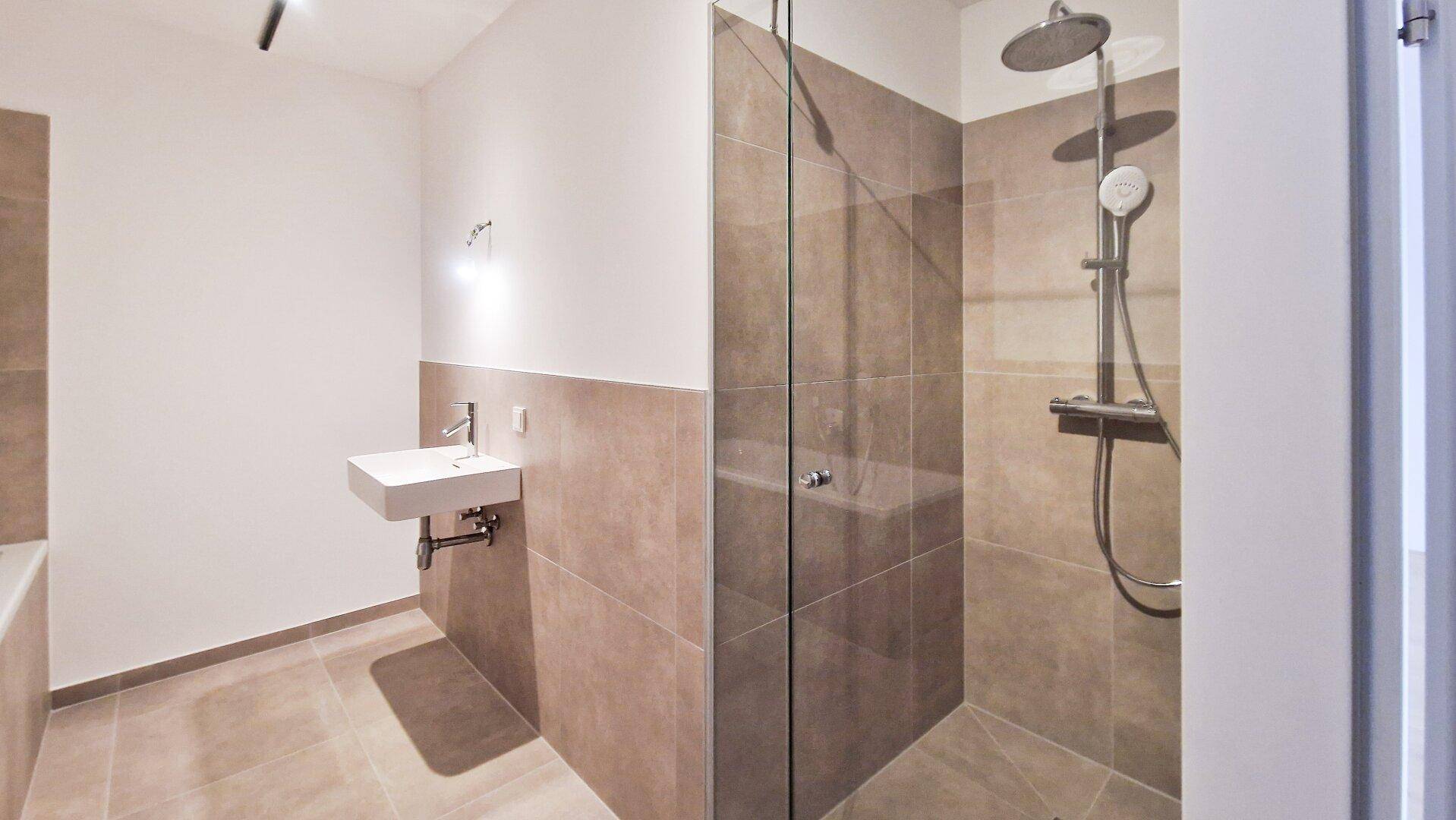 Helles Badezimmer mit moderner Duschkabine, Regenbrause und schwebendem Waschbecken.