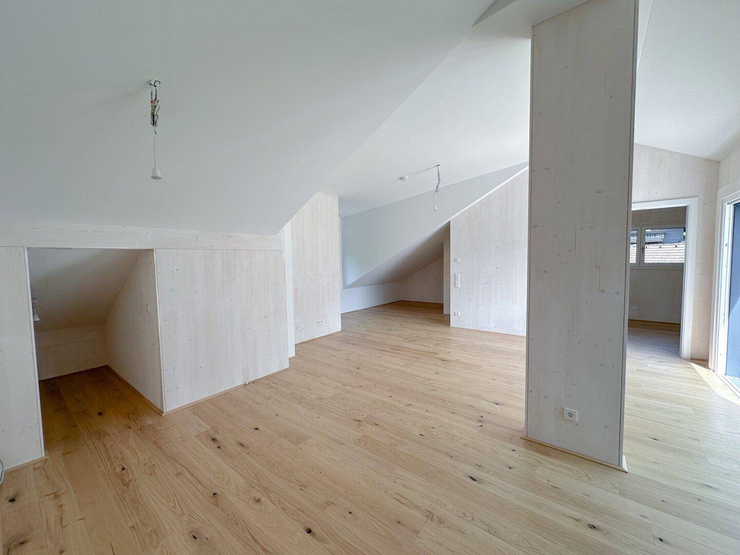 Geräumiger Innenraum mit Holzboden und Dachschrägen, bereit für die individuelle Gestaltung.