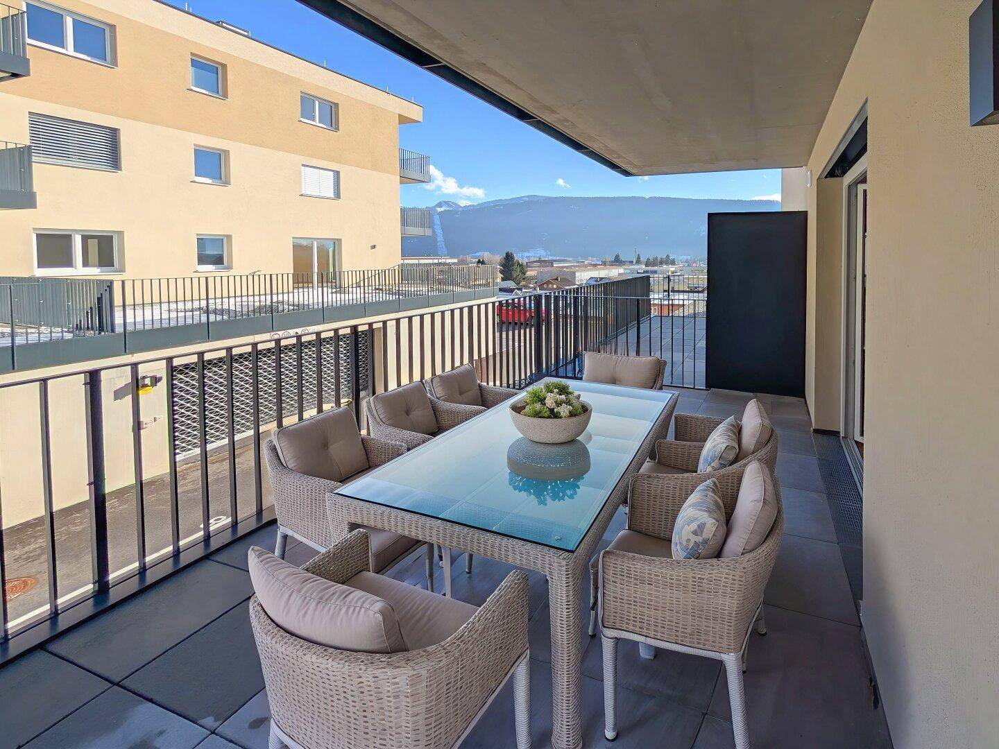 Geräumiger Balkon mit Esstisch, bequemen Sitzgelegenheiten und weitem Bergblick.