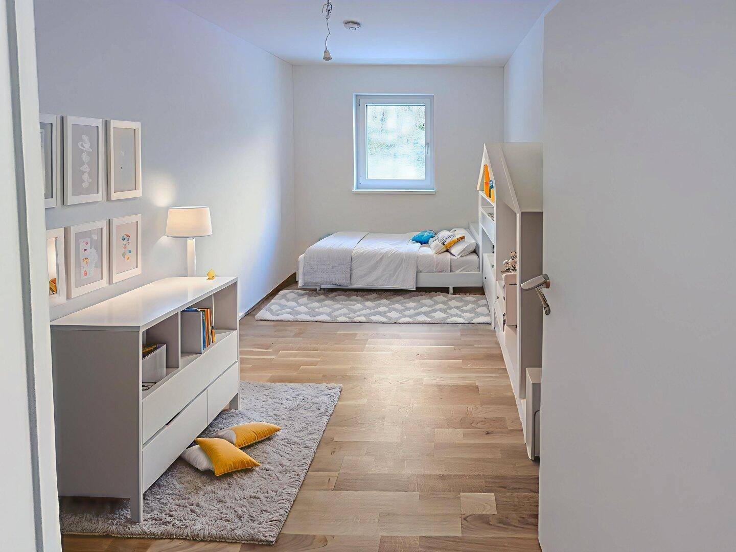 Helles Kinderzimmer mit Holzboden, modernem Bett und minimalistischer Einrichtung.