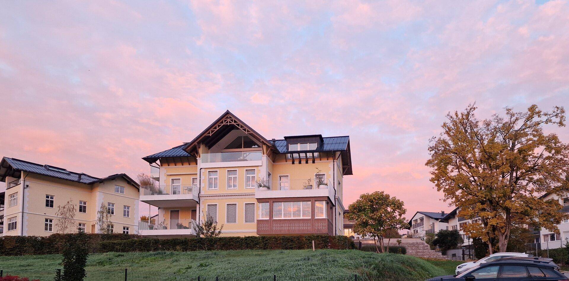 Elegantes Gebäude mit klassischer Architektur bei Sonnenuntergang und rosa Himmel.