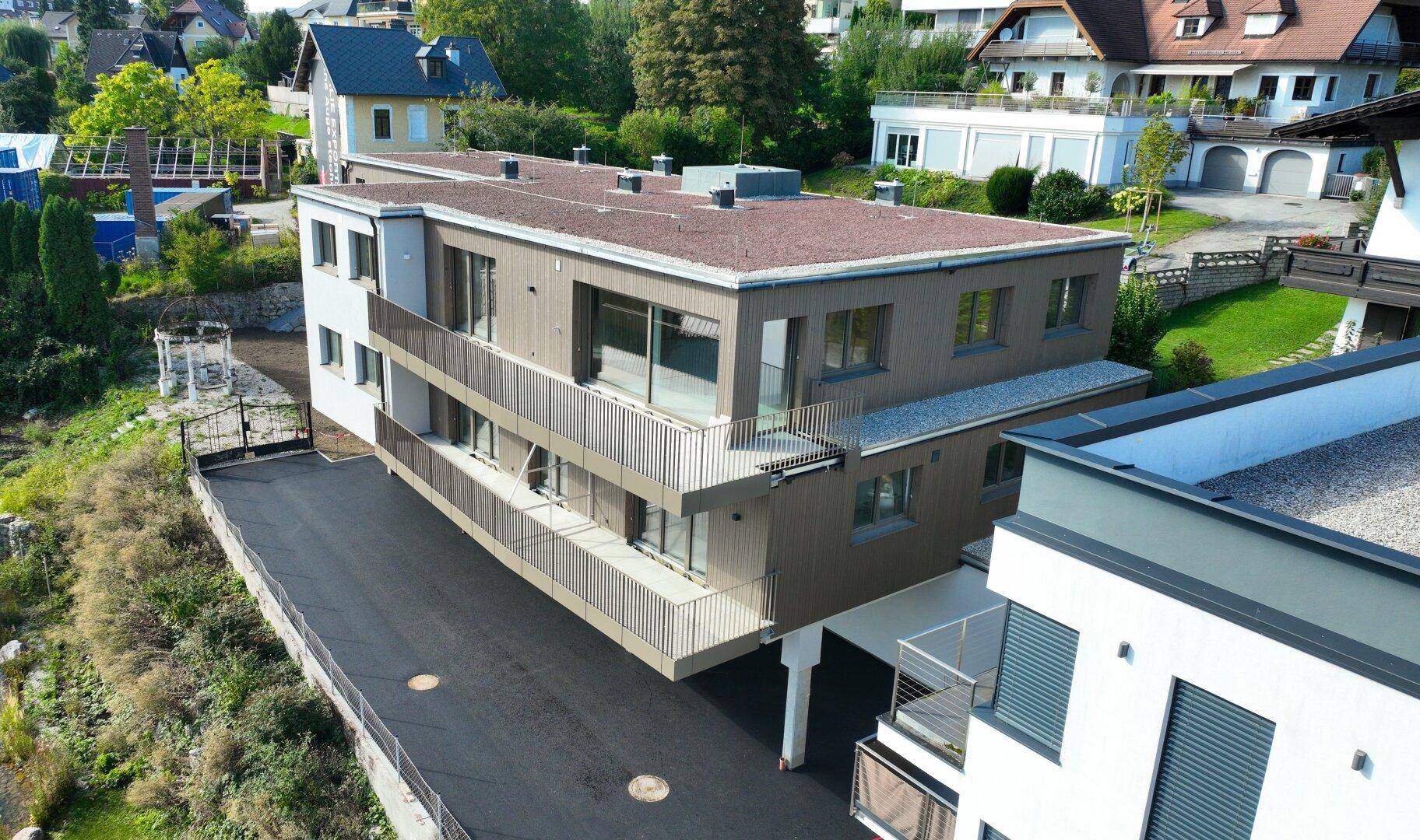Luftaufnahme des modernen Gebäudes mit Flachdach, Balkonen und umliegender Grünfläche.