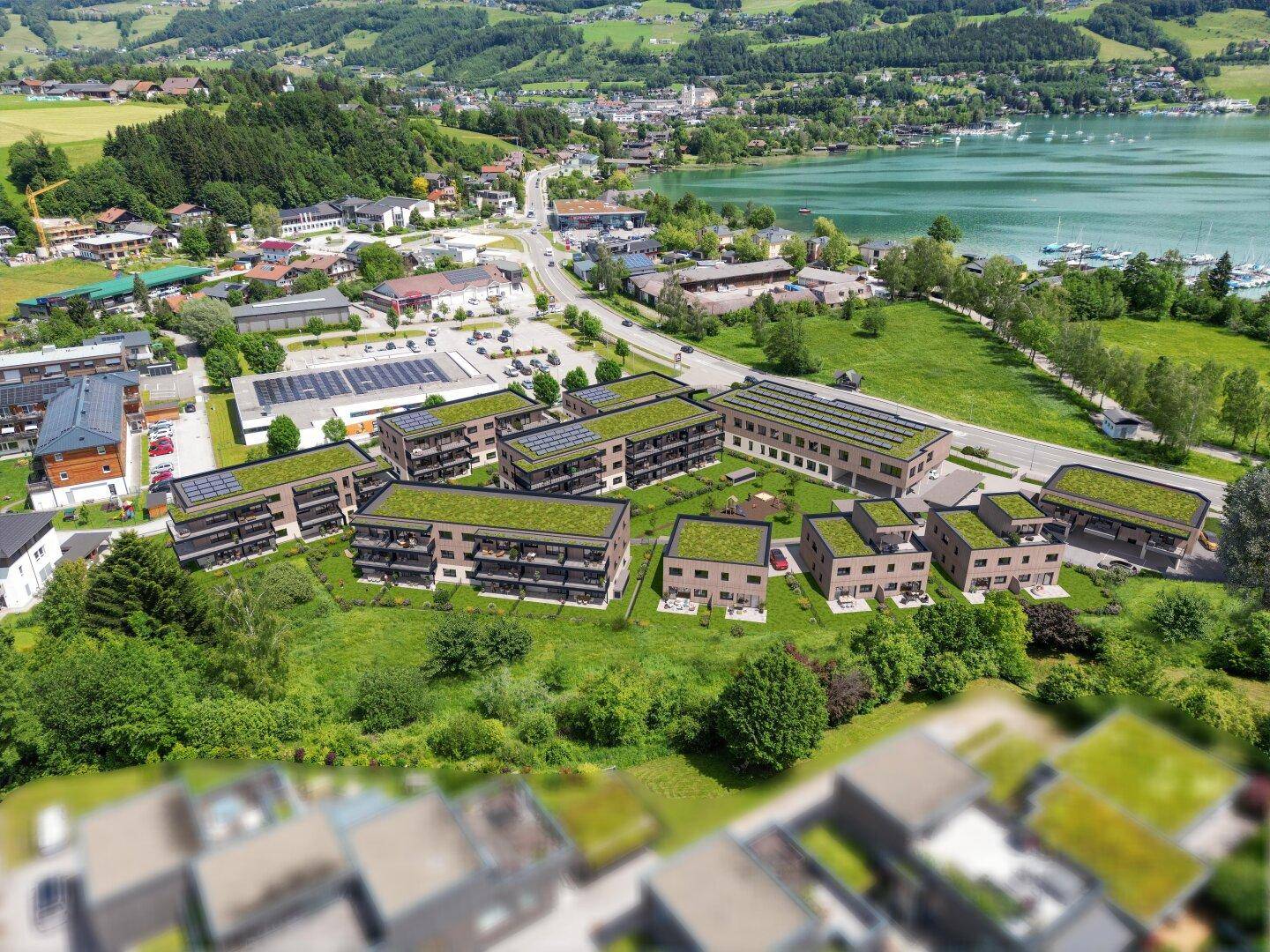 Nahaufnahme einer modernen Wohnanlage mit Gründächern und Balkonen in Seenähe.