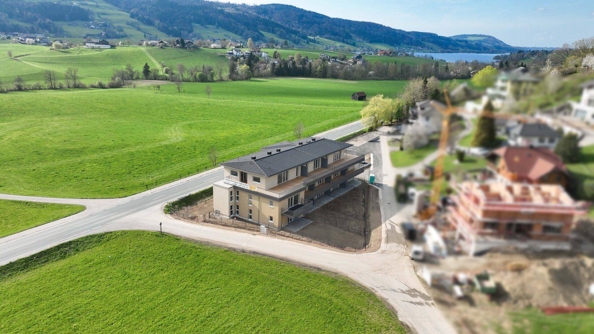 Neubau-Wohnhaus in idyllischer Landschaft mit weitem Blick über grüne Felder und einen See.