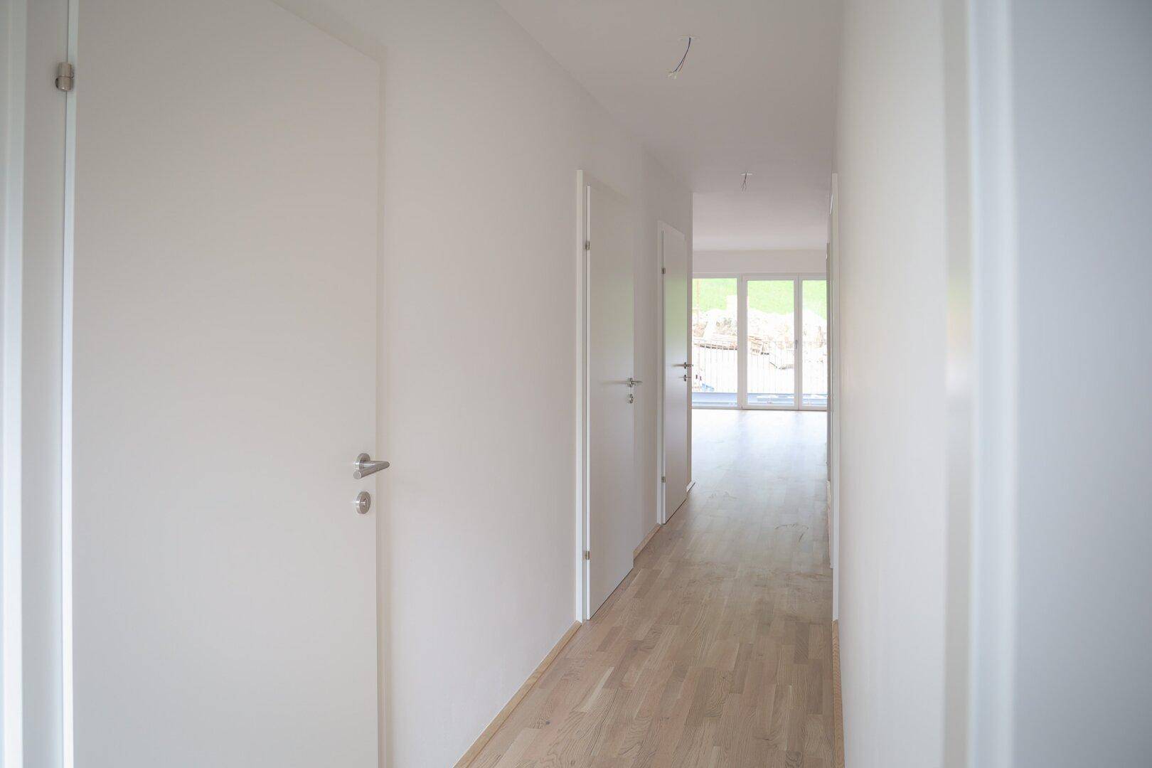 Heller Flur mit Holzboden und mehreren Türen, der zu weiteren Räumen führt.