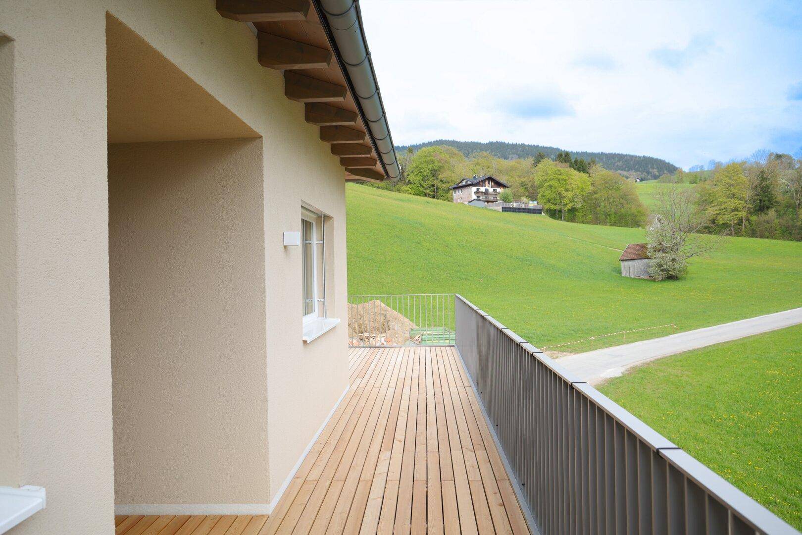 Geräumige Holzterrasse mit weitem Blick über die grüne Hügellandschaft und die Natur.
