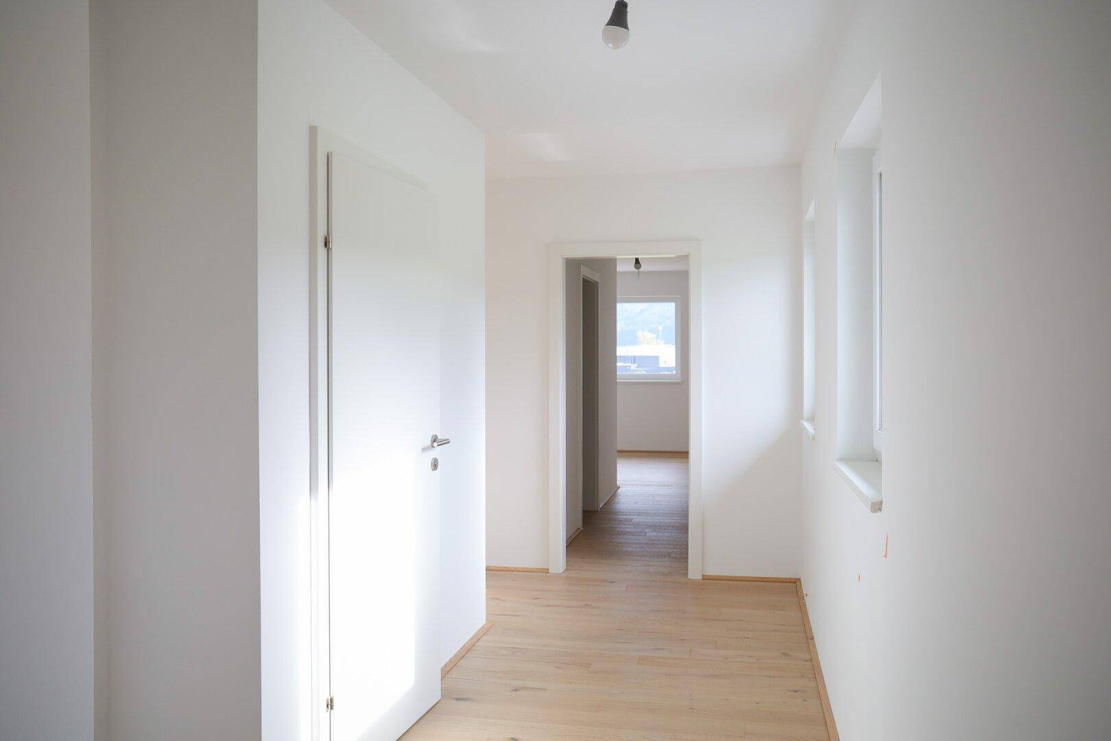 Heller Flur mit Holzboden und Türen zu weiteren Zimmern, gut beleuchtet.
