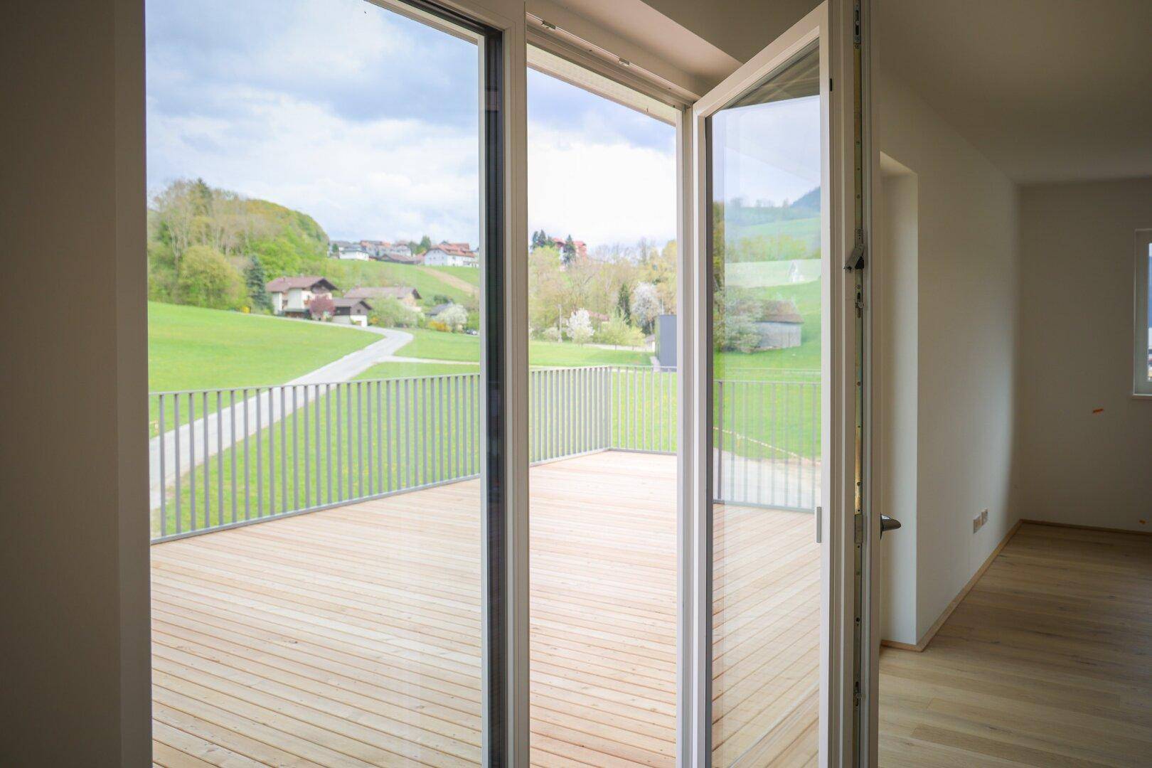 Große Terrassentüren öffnen den Wohnbereich zur grünen Landschaft und bieten viel Licht.