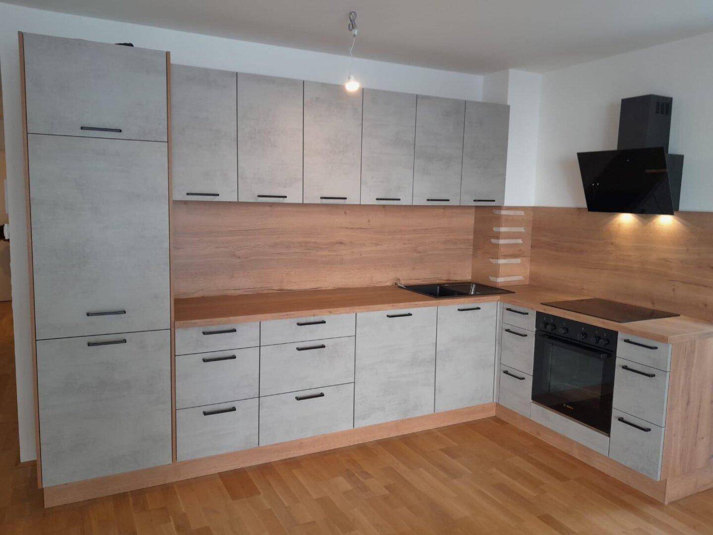 Moderne Einbauküche mit grauen Fronten, Holzdetails und integrierten Geräten.