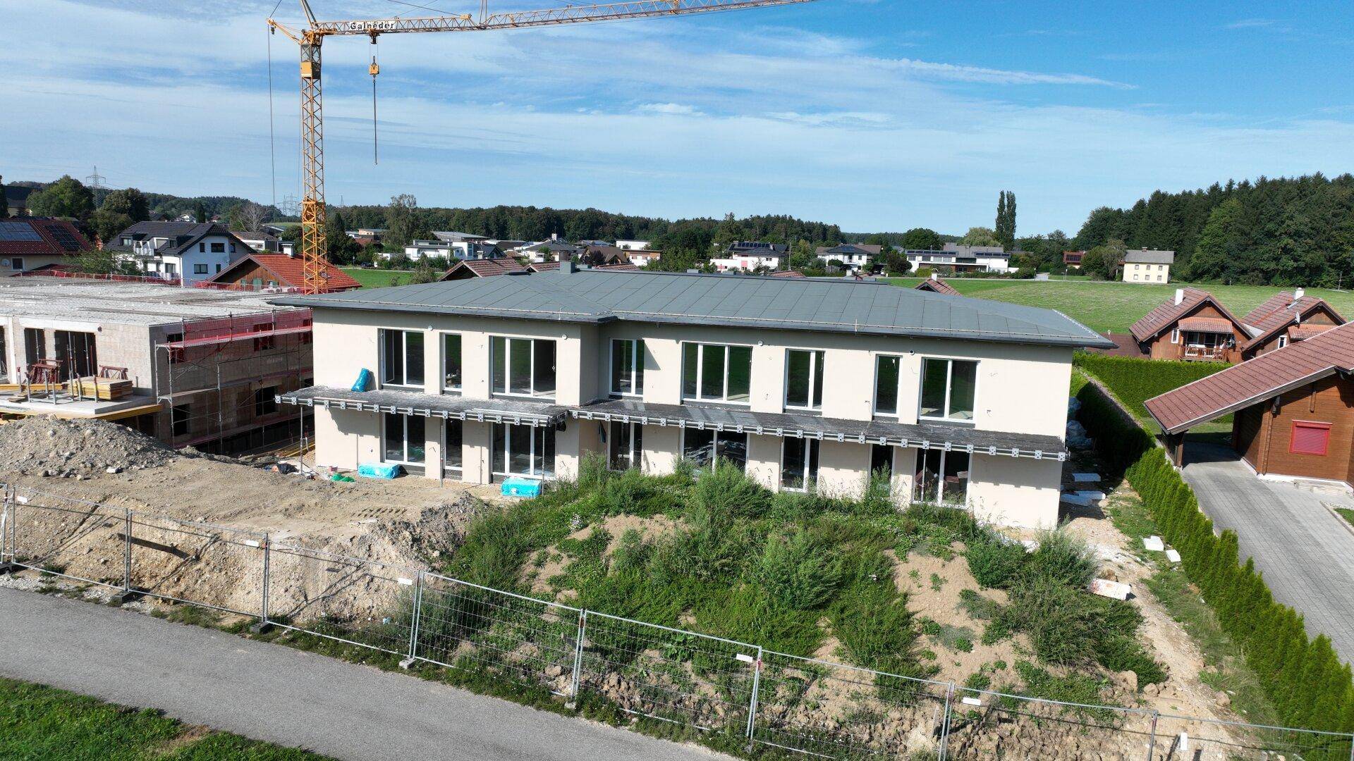 Neubau eines Mehrfamilienhauses im Rohbau mit sichtbarem Baukran im Hintergrund.