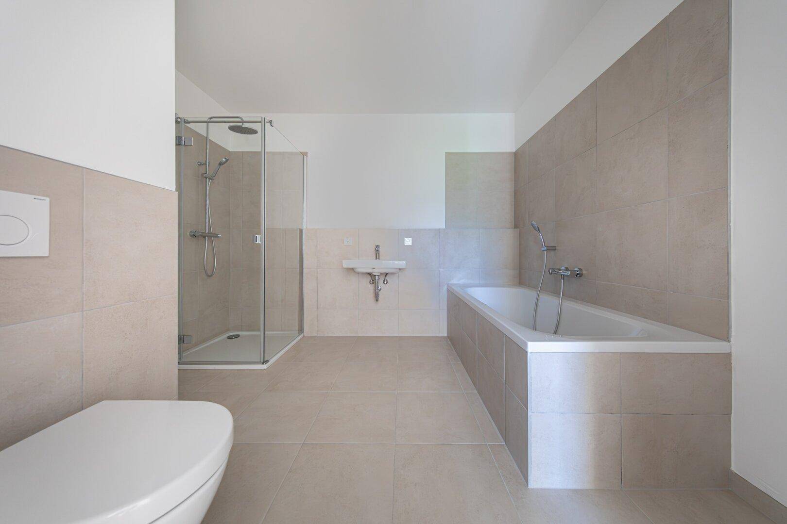 Modernes Badezimmer mit Dusche, Badewanne, Wand-WC und beigefarbenen Fliesen.