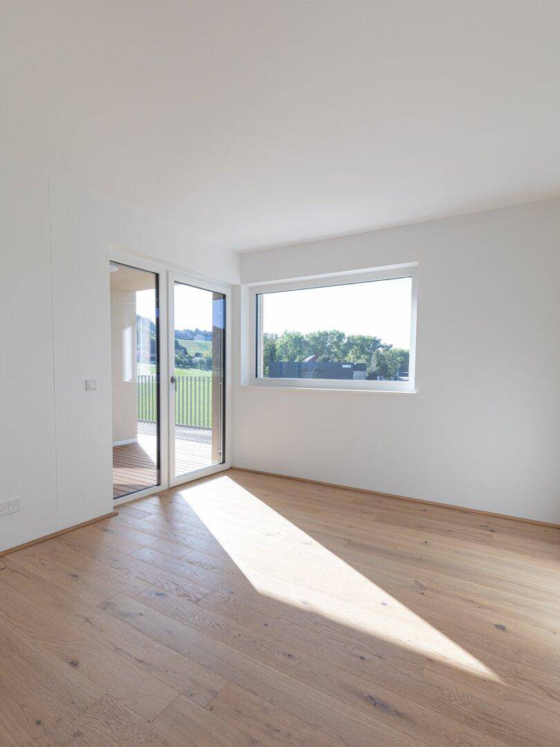 Helles Zimmer mit Holzboden, großem Fenster und viel natürlichem Licht.