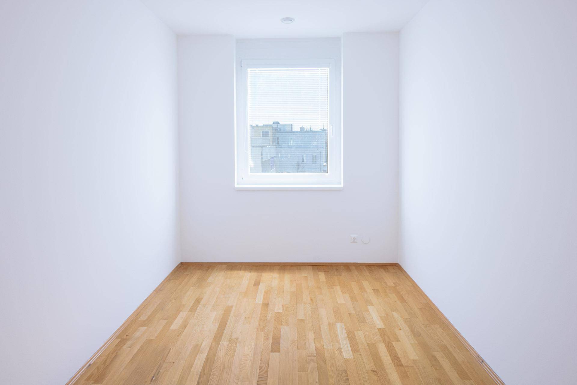 Kleines, helles Zimmer mit Parkettboden und einem Fenster, ideal als Kinder- oder Arbeitszimmer.